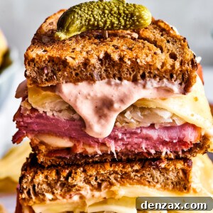 Two Reuben sandwich halves with Russian dressing dripping from one.