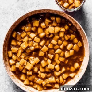 Homemade apple pie filling in a white skillet, and a small jar of the filling set right next to the skillet.