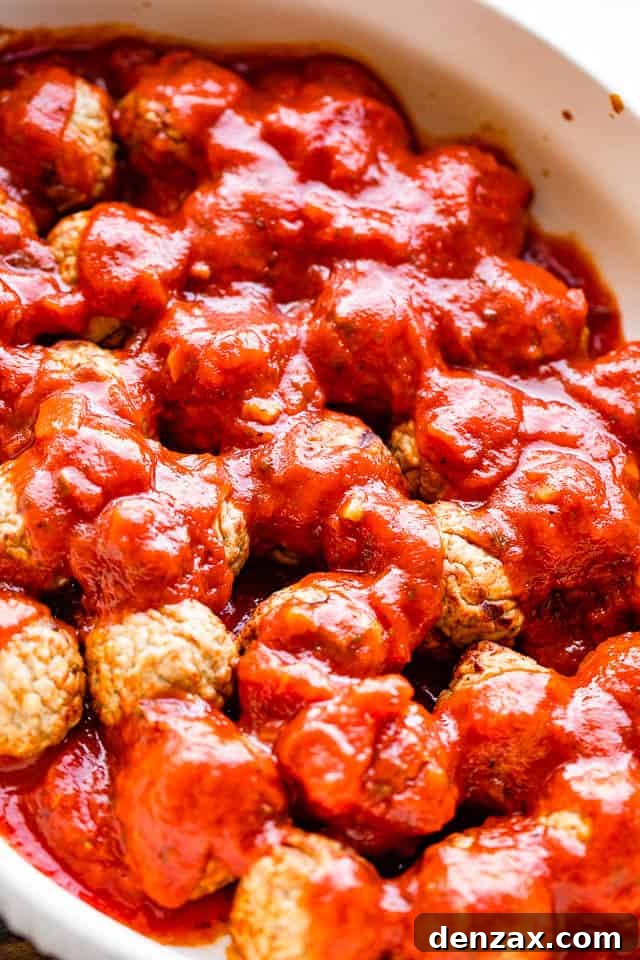 pouring marinara sauce over meatballs