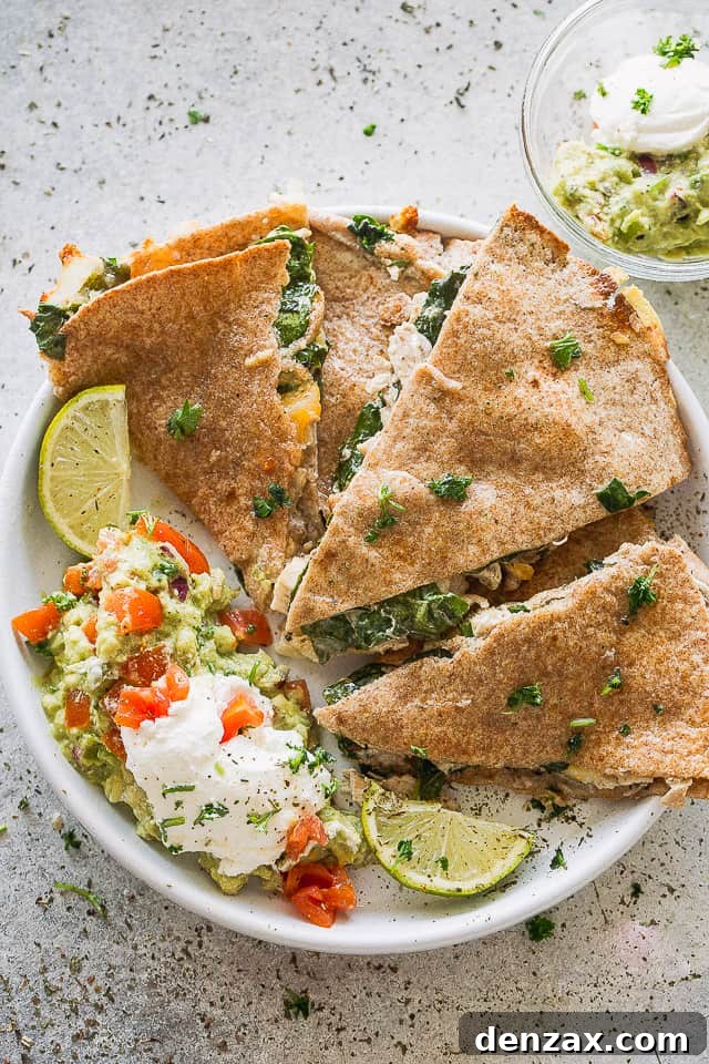 A plate of baked quesadillas with sour cream and guac.
