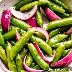 roasted sugar snap peas with red onions served in a cream bowl