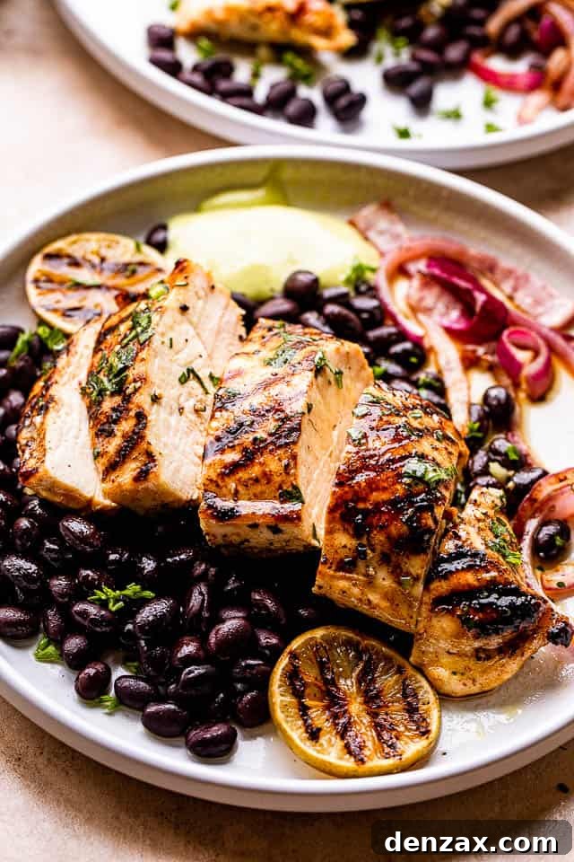 Grilled Mojo Chicken Breast cut in slices and served over black beans and guacamole to the side.