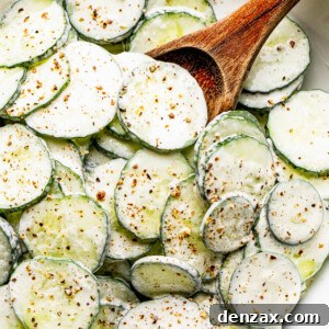 salad bowl filled with sour cream covered cucumbers sprinkled with cracked black pepper