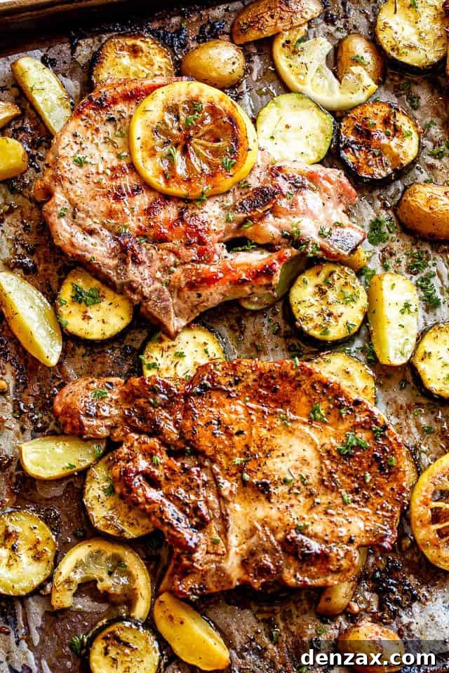 sheet pan with baked pork chops on top of slices of squash and lemons