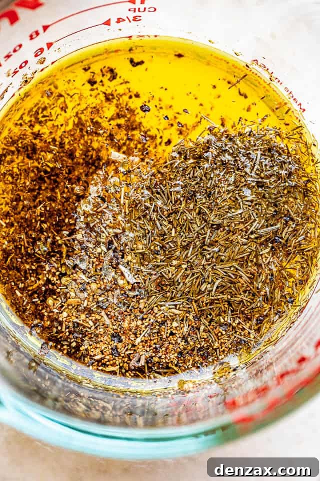 glass measuring cup filled with lemon dressing mixture with dried herbs