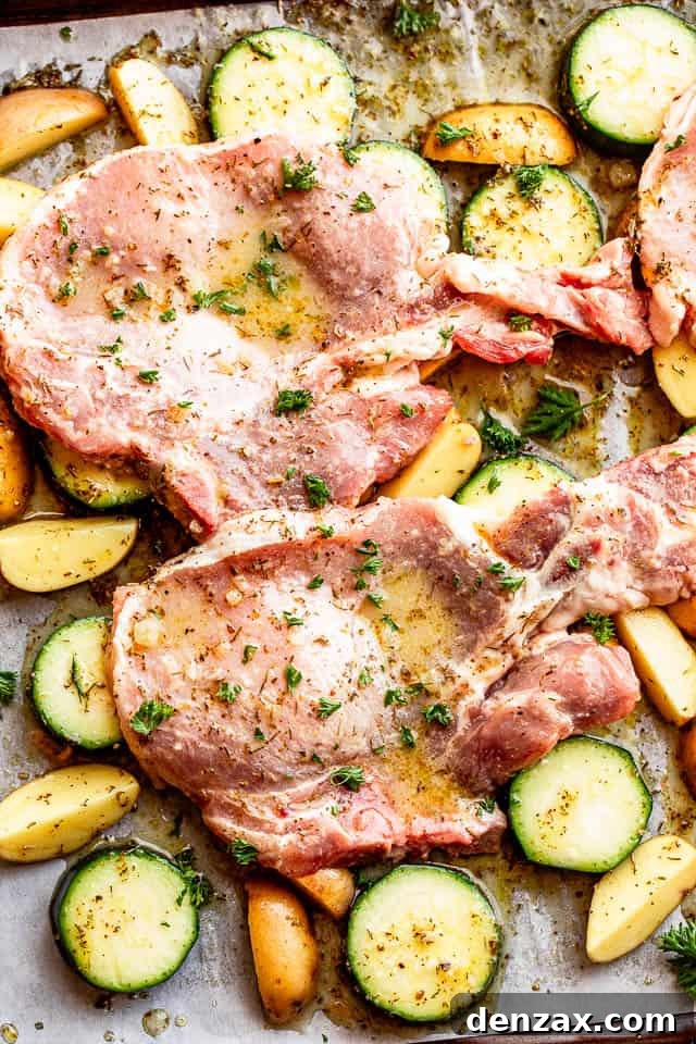 baking sheet with raw pork chops set on top of squash slices