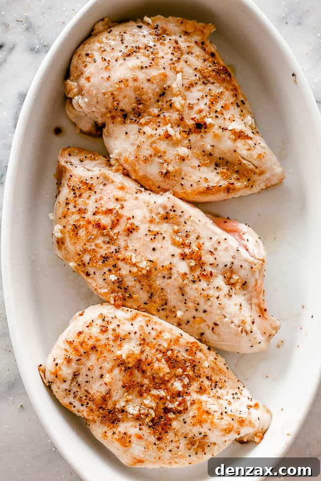 Oven-Baked Caesar Chicken with Crispy Parmesan Crust 3 top view of seasoned chicken breasts in a white oval baking dish