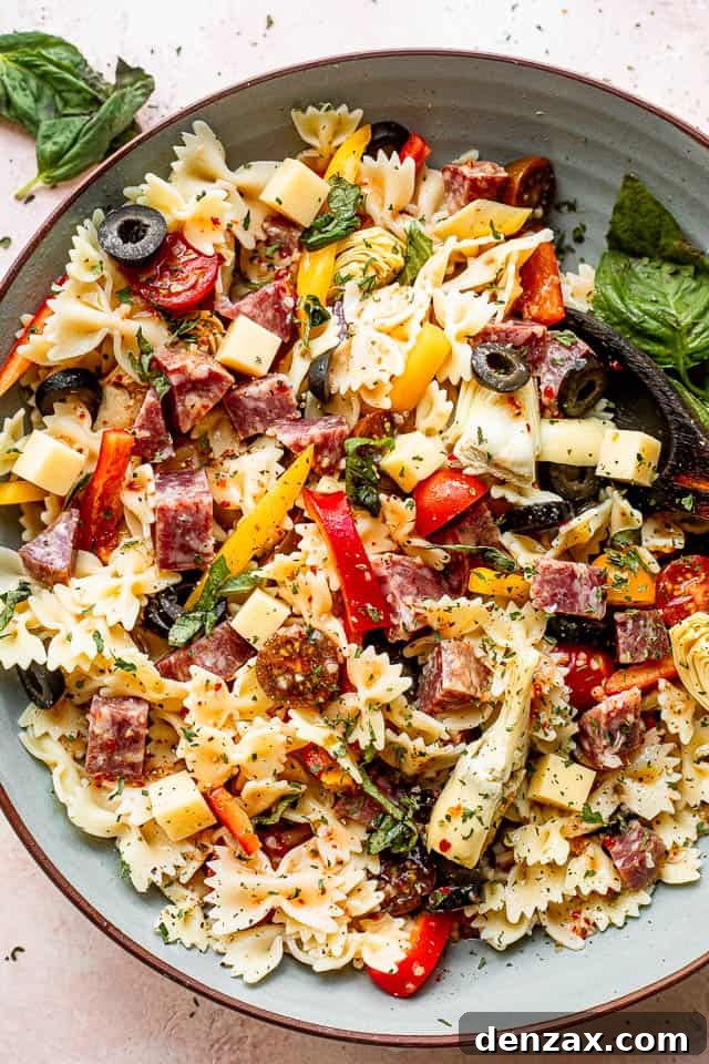 top view of a large blue salad bowl with pasta, olives, cheeses, and salami