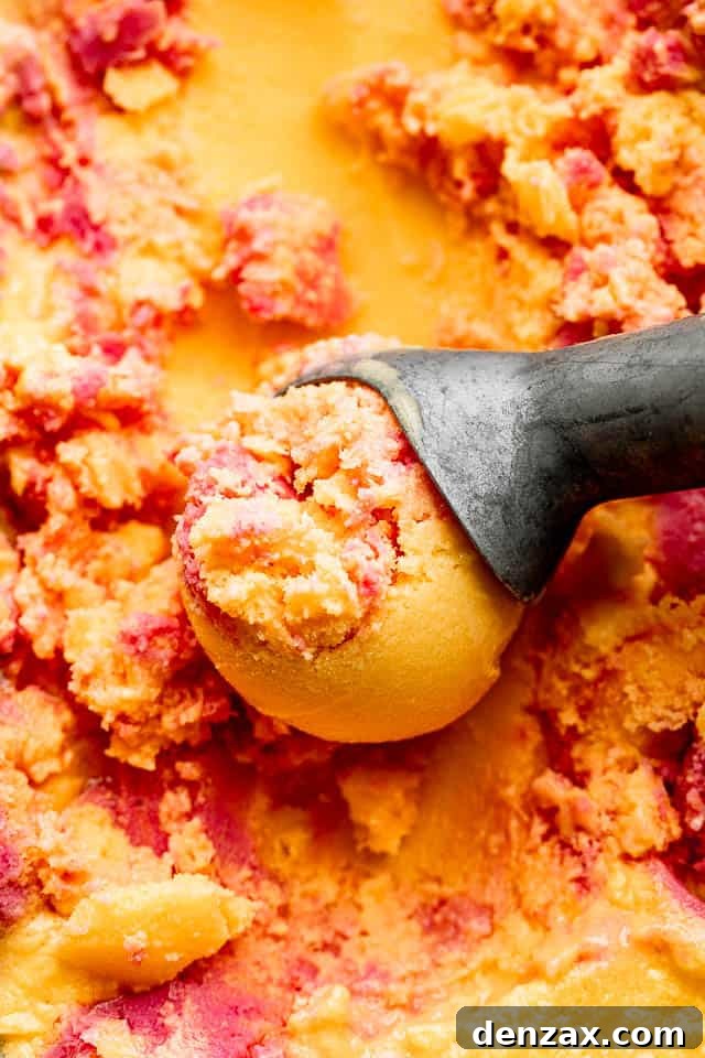 close up shot of mango strawberry frozen yogurt in an ice cream scoop
