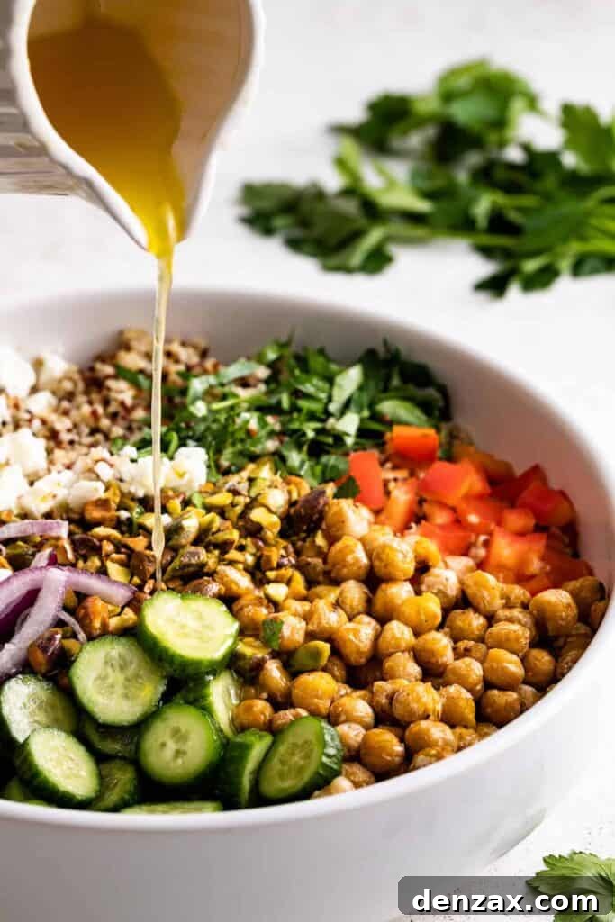 Drizzled with homemade dressing, this Jennifer Aniston quinoa salad with crunchy chickpeas is super light and refreshing. Pouring the dressing into the salad.