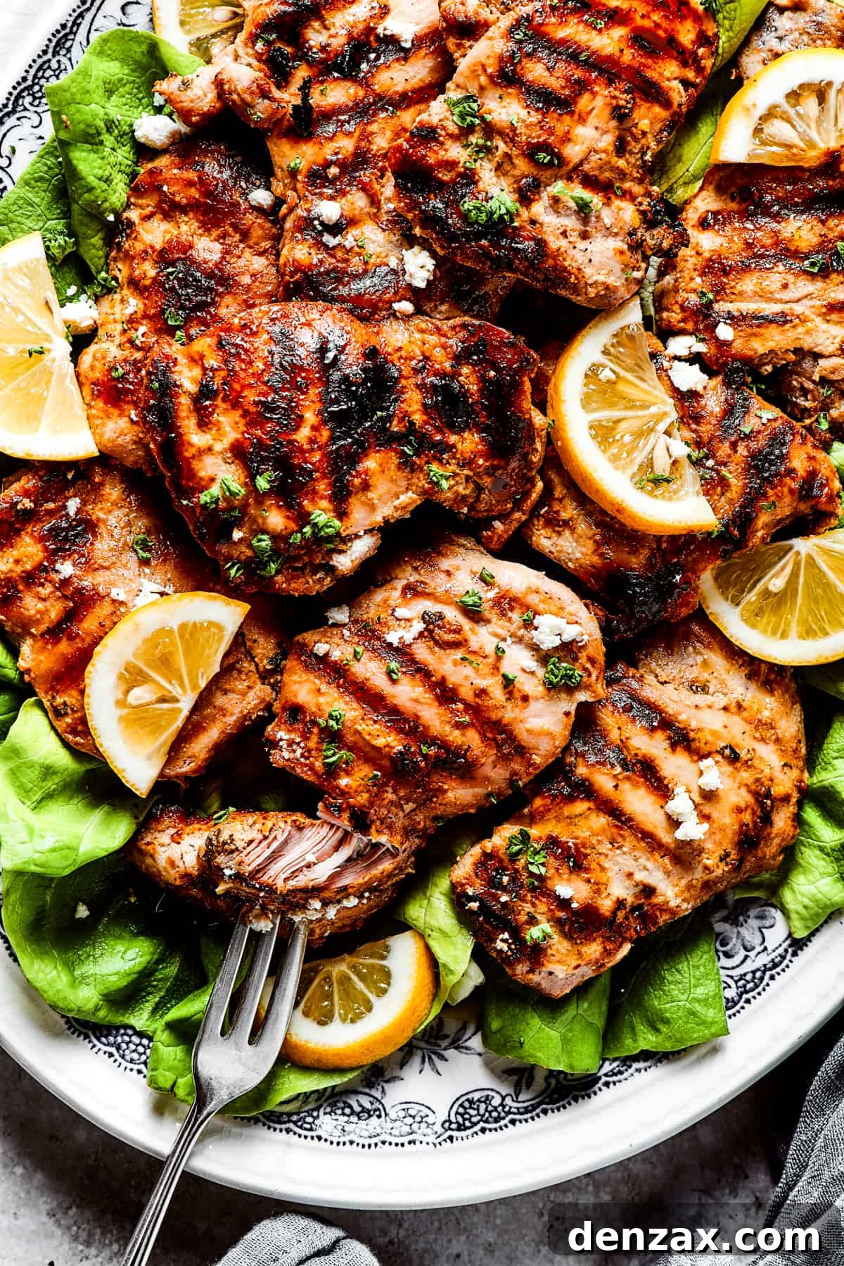 Pulling a piece of grilled chicken apart with a fork.