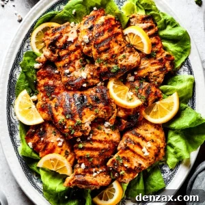 Grilled chicken thighs and lemon slices on a bed of salad greens.