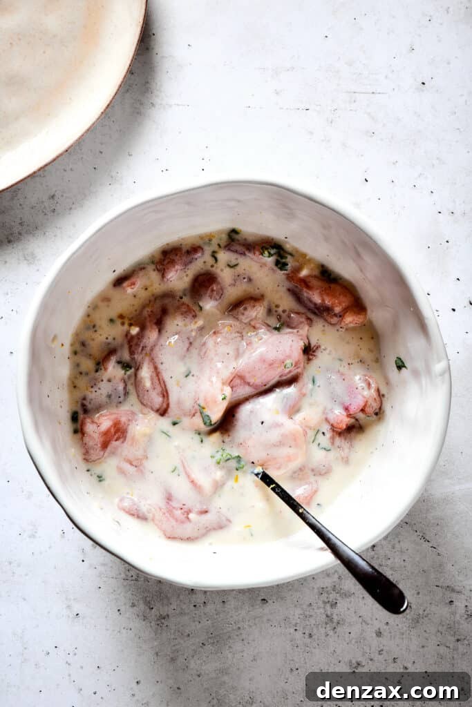 Adding chicken to yogurt marinade.