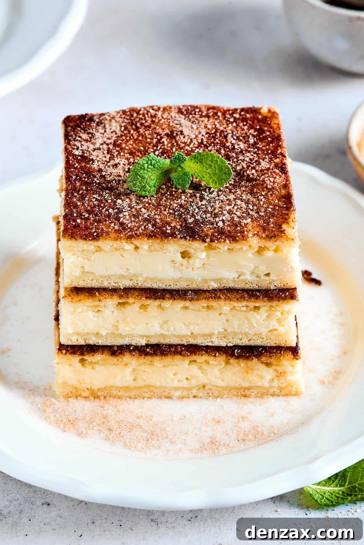 Three stacked cheesecake bars with cinnamon topping and mint leaves.
