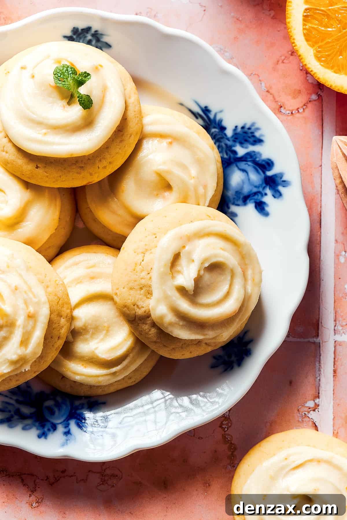 A blue and white flowered plate with iced orange cookies.