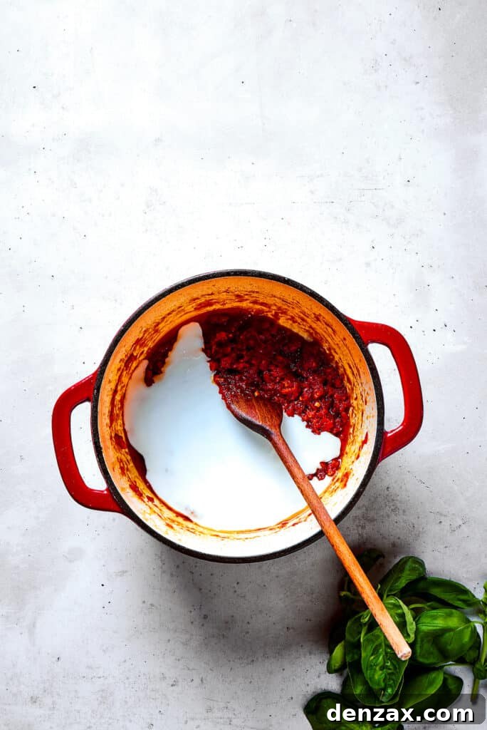 Stirring cream into a pot of sauce.