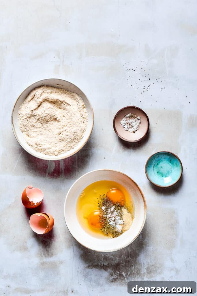A bowl of breading ingredients next to a bowl of beaten eggs and seasonings.