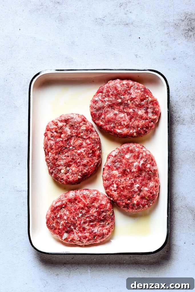 Shaped beef patties on an enamel tray.