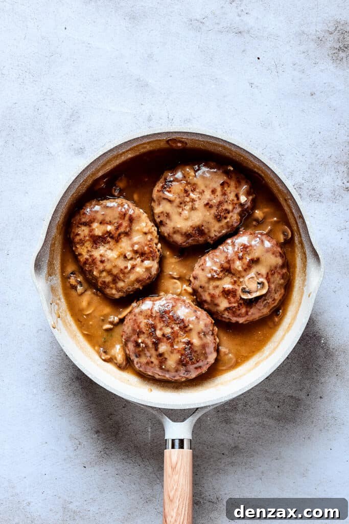 A finished skillet of beef patties with gravy.
