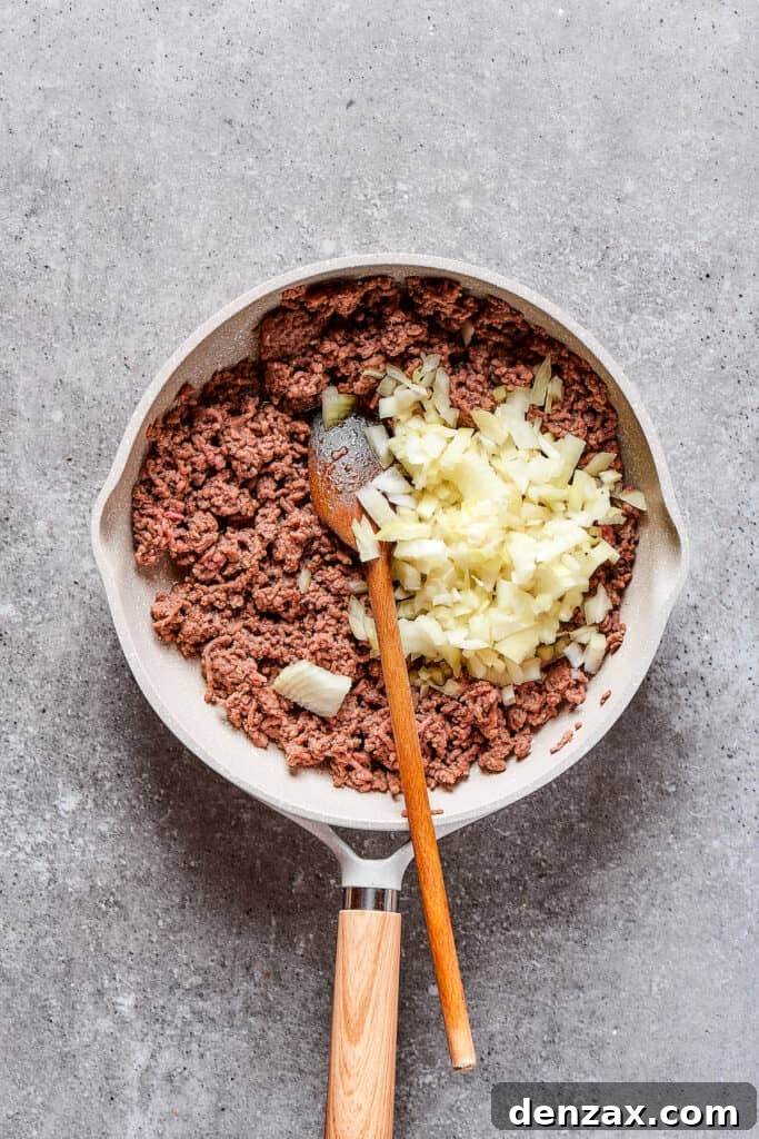 Adding onion to a skillet of ground beef.