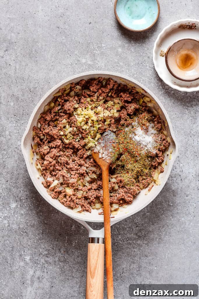 Adding seasonings to a skillet of beef and onions.