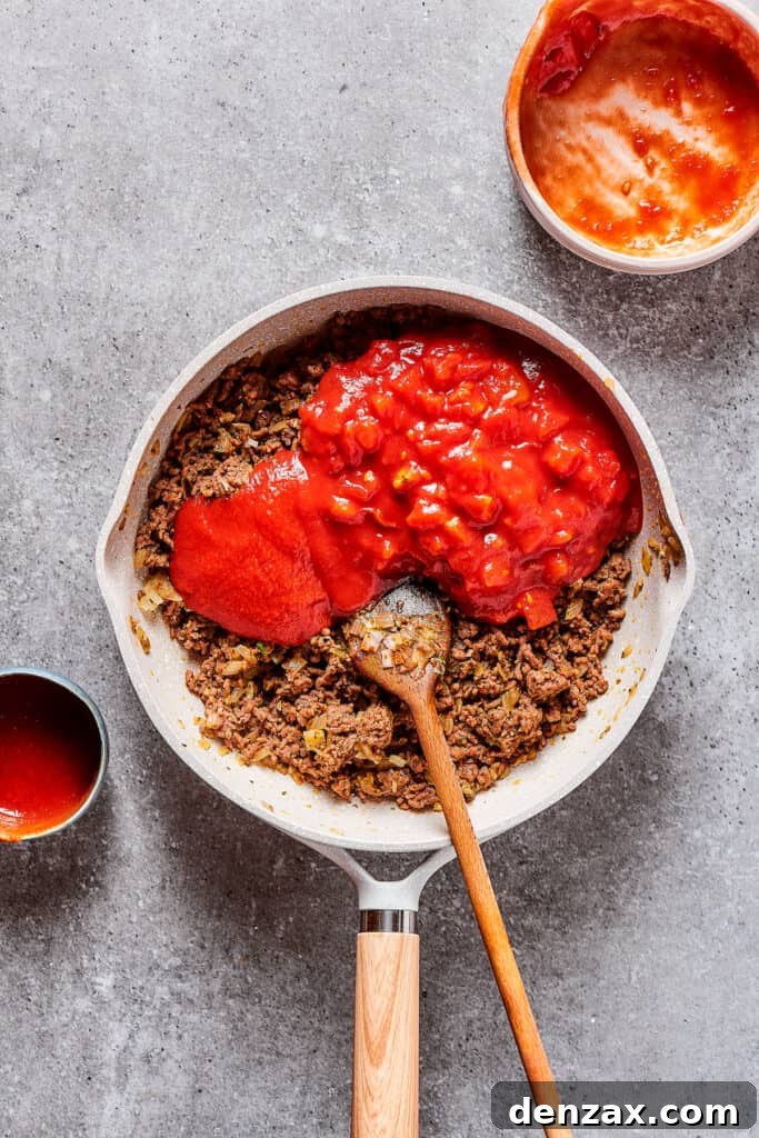 Tomato puree and diced tomatoes in a skillet with ground beef.