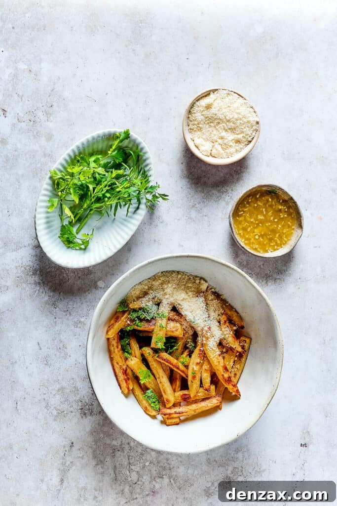 Baked fries in a bowl next to bowls of melted butter with garlic, parmesan, and parsley.