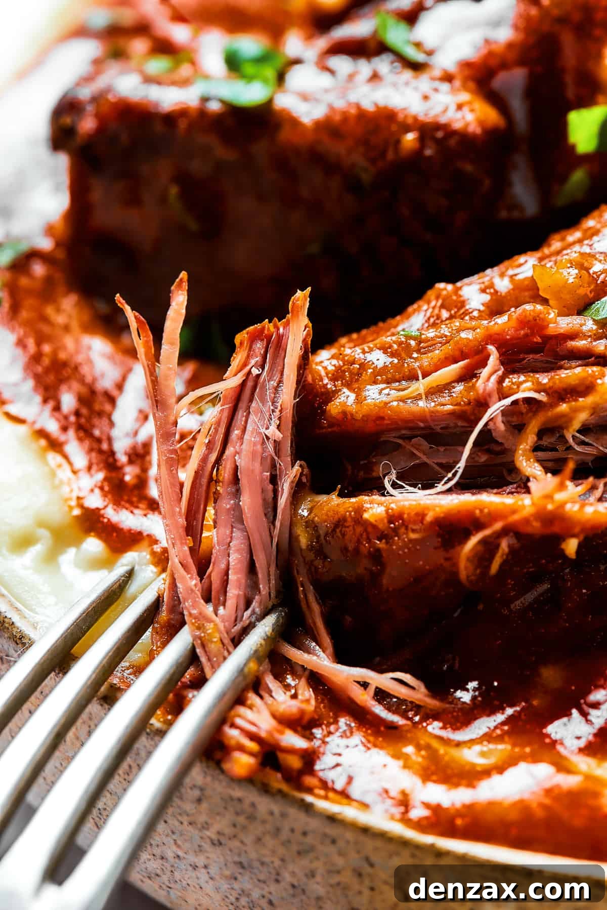 Short ribs pulled apart slightly by a fork.