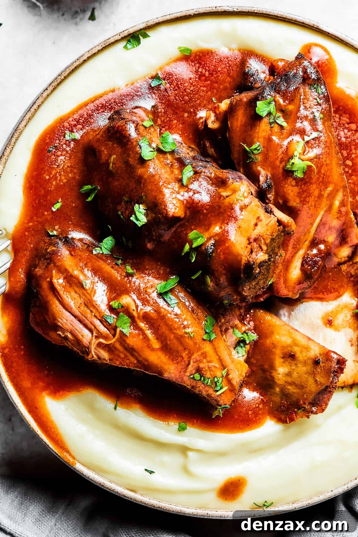 Close-up of Instant Pot short ribs topped with sauce and arranged atop mashed potatoes.