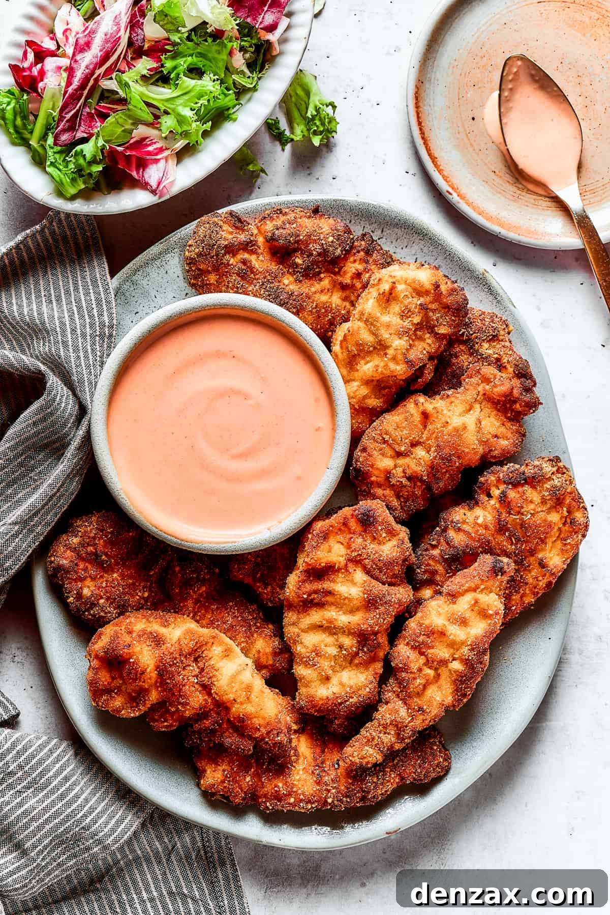 Yum Yum Sauce is a scrumptious, creamy condiment that adds a burst of flavor to any dish. You'll love this sweet, tangy Japanese sauce! A platter of chicken strips with sauce.