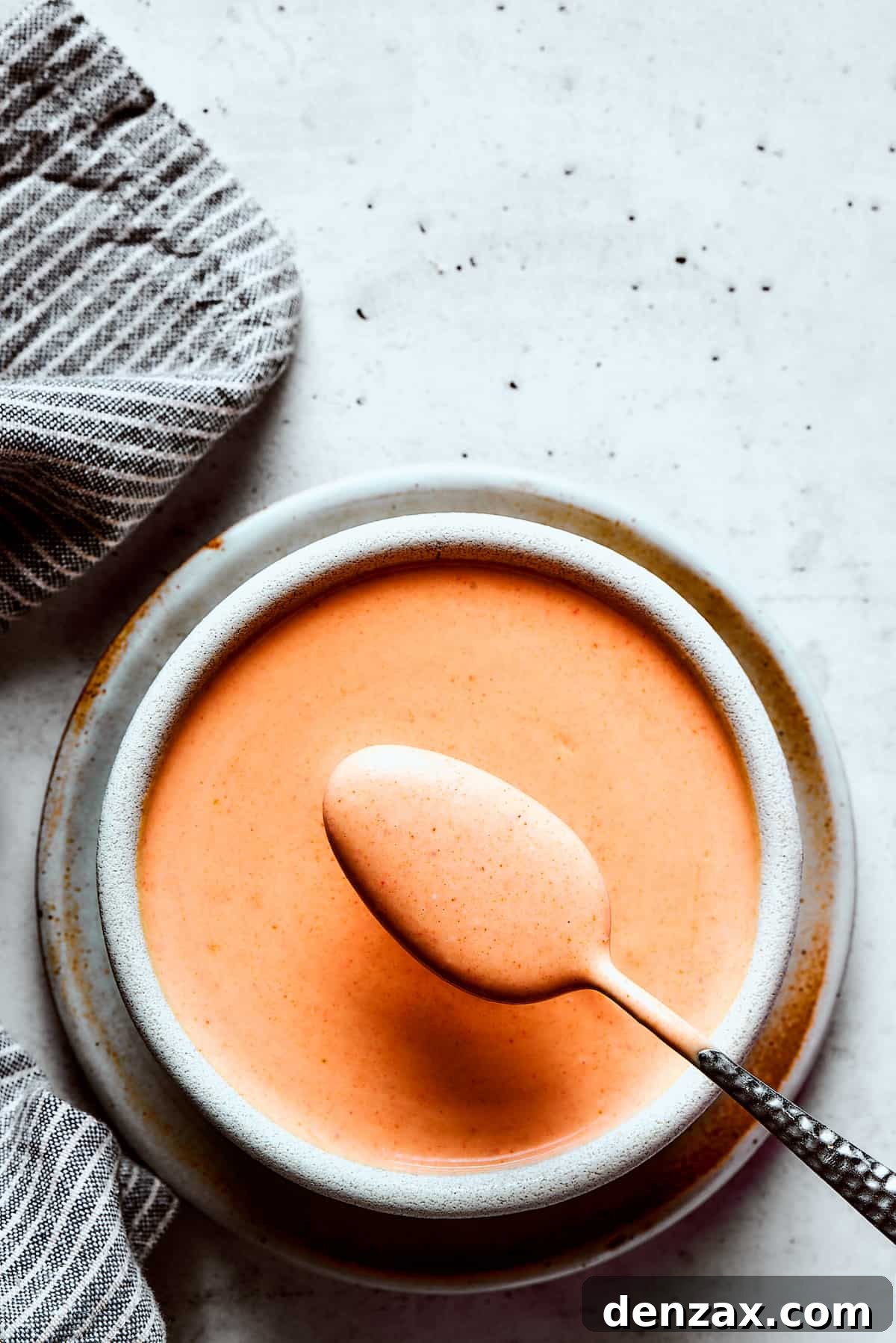 Yum Yum Sauce is a scrumptious, creamy condiment that adds a burst of flavor to any dish. You'll love this sweet, tangy Japanese sauce! Lifting a spoonful of sauce toward the camera.