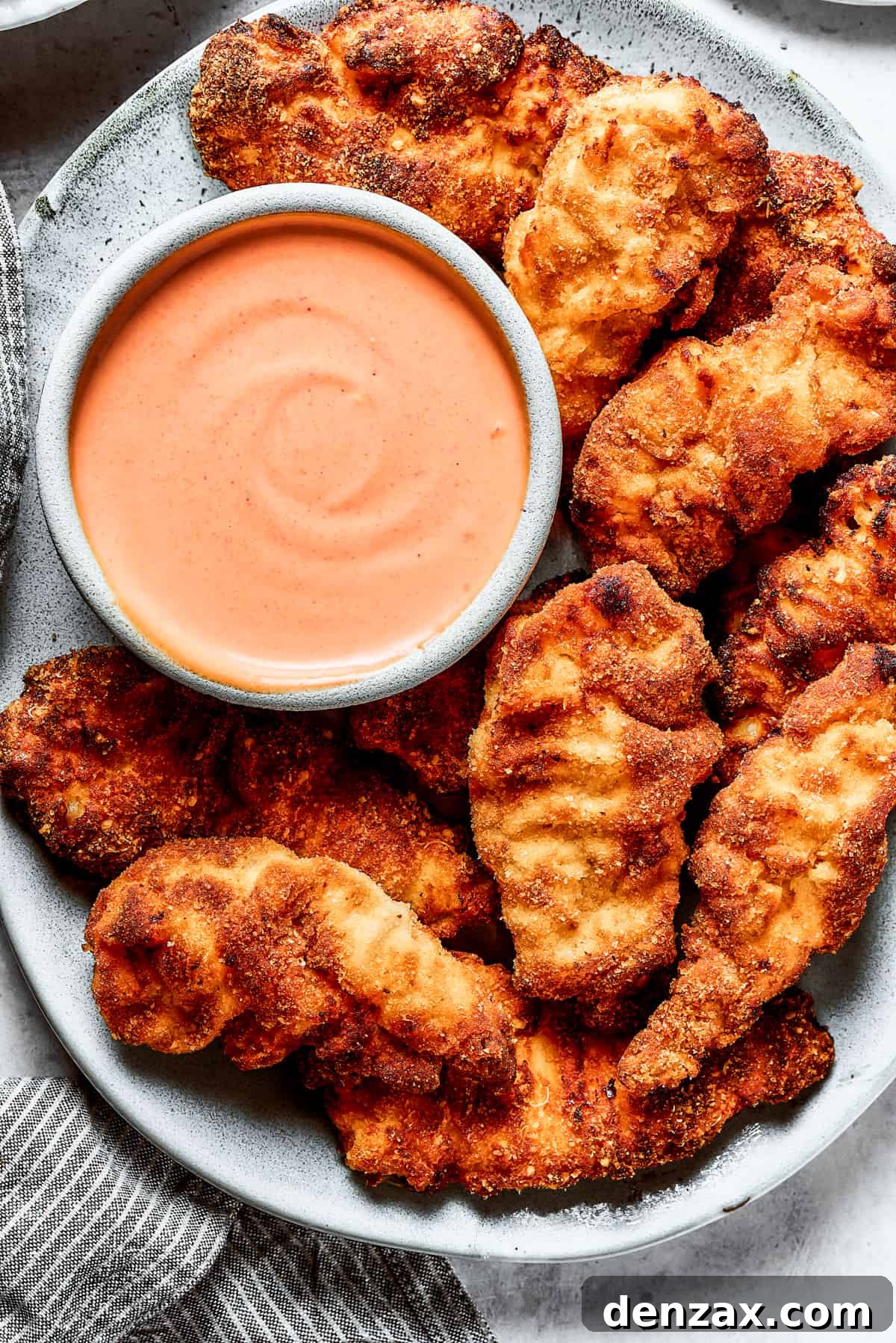 Yum Yum Sauce is a scrumptious, creamy condiment that adds a burst of flavor to any dish. You'll love this sweet, tangy Japanese sauce! A platter of chicken strips with sauce.