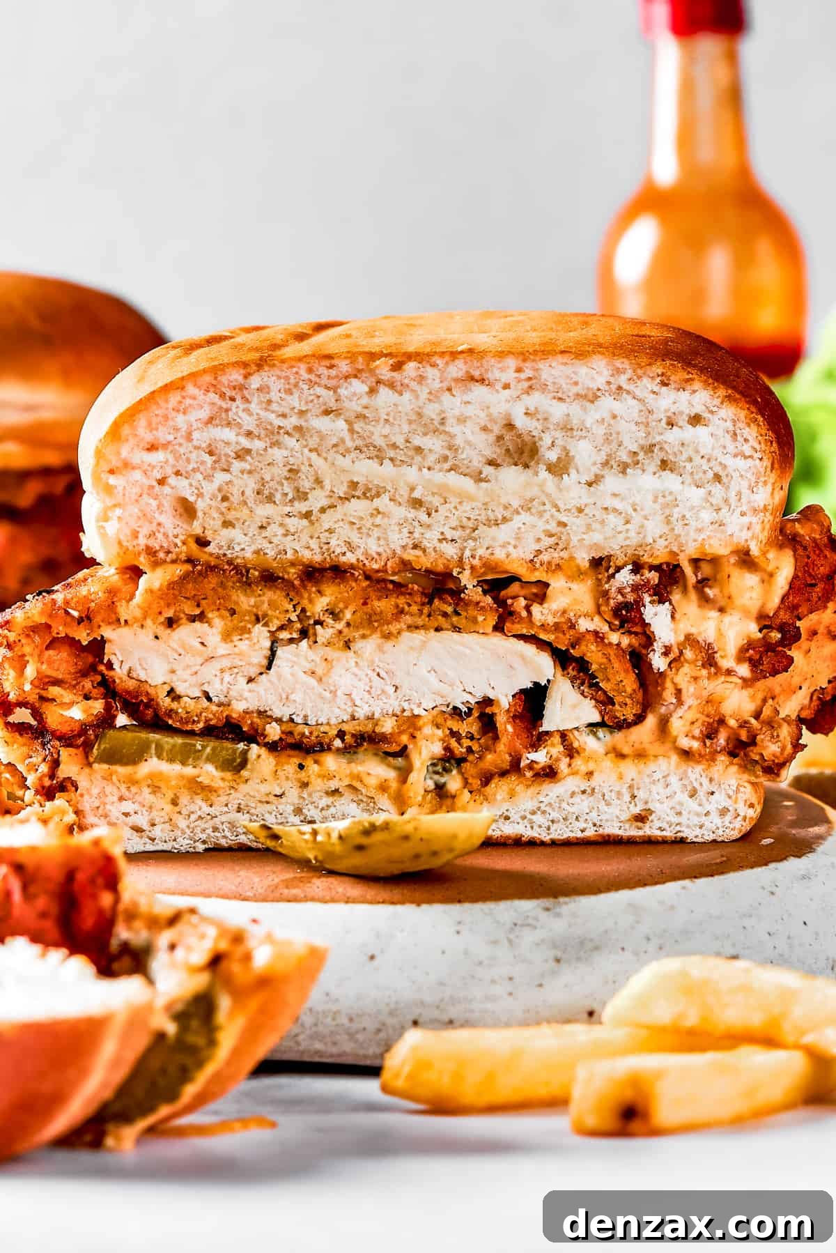 A homemade fried chicken sandwich cut in half to show the texture of the fried chicken and bun.