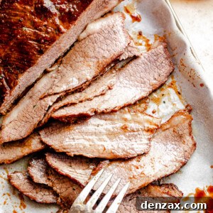 top view of sliced beef brisket with a silver fork placed at the bottom slice and a jar with barbecue sauce to the side