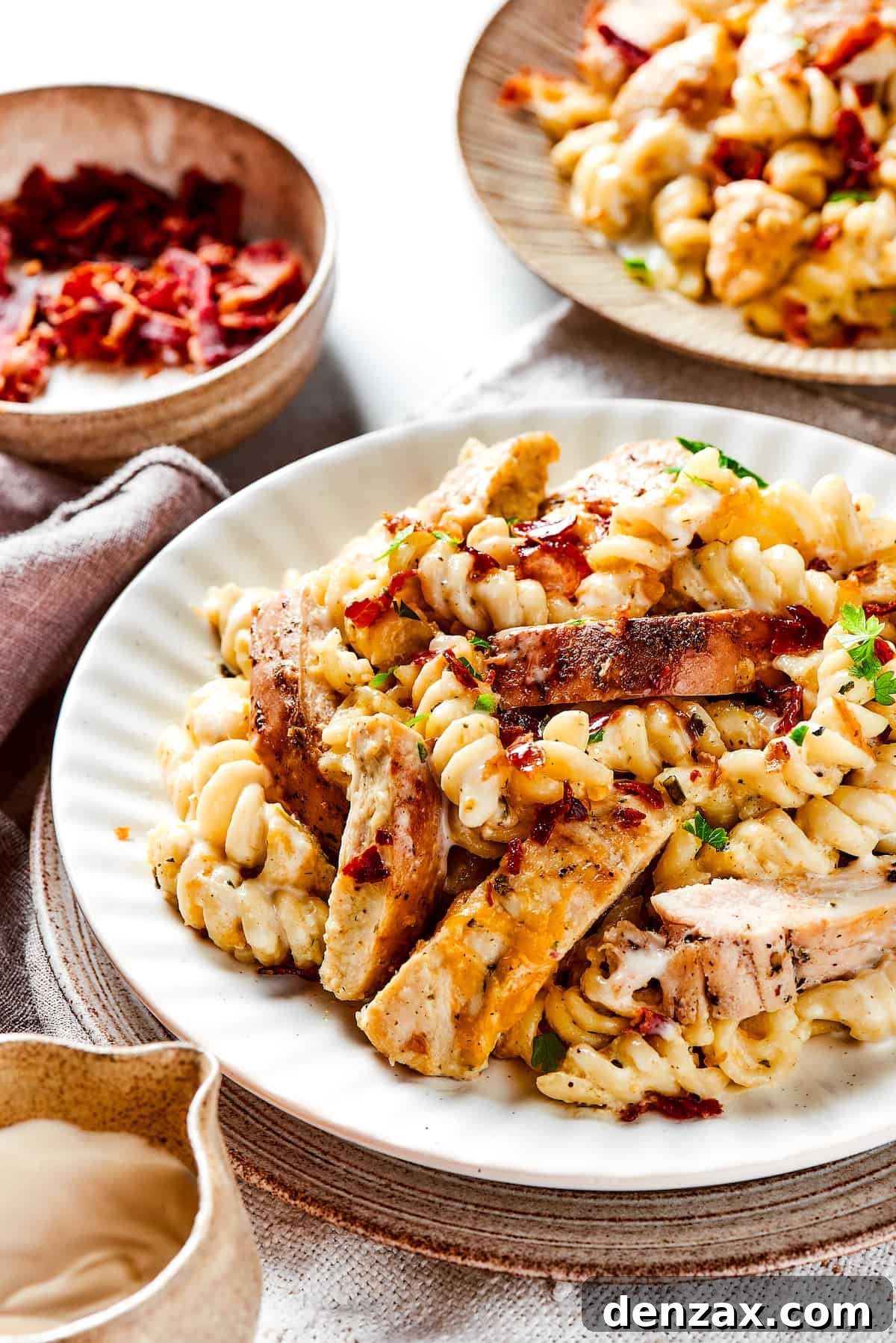 This bold and creamy Chicken Bacon Ranch Pasta recipe is a savory, smoky dinner dish that's bursting with flavor! The best comfort food! Chicken bacon ranch pasta on dinner plates.