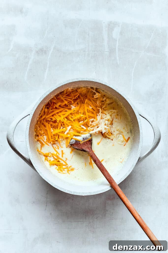 Stirring cheddar cheese into a hot cream mixture to make cheese sauce.