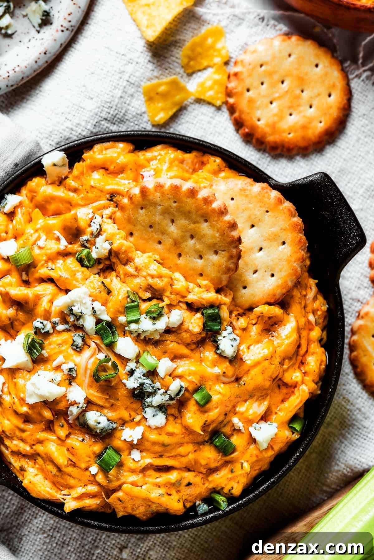 With its creamy, cheesy, spicy goodness, Crockpot Buffalo Chicken Dip is a favorite for parties, game days, movie night, and more! Overhead shot of a serving of buffalo dip with crackers, blue cheese, and green onions.