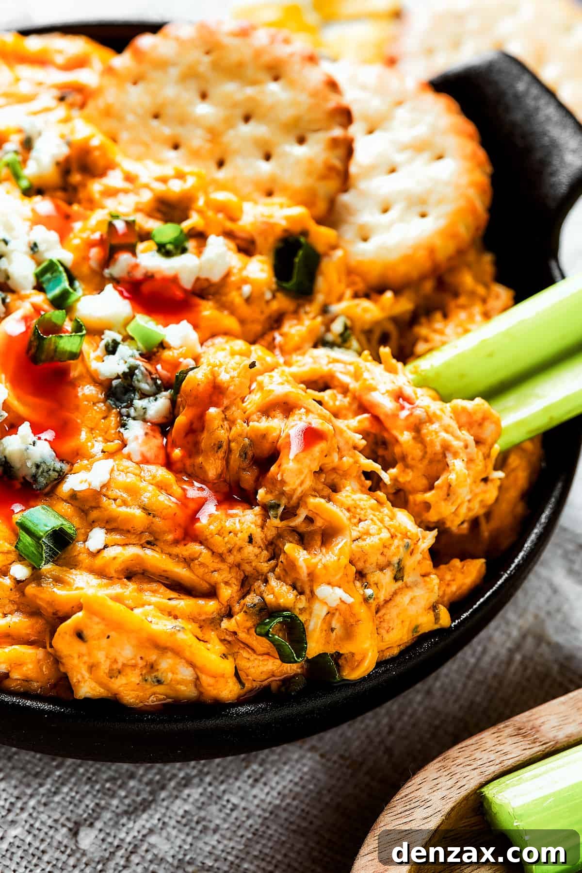 With its creamy, cheesy, spicy goodness, Crockpot Buffalo Chicken Dip is a favorite for parties, game days, movie nights, and more. A small, two-handled dish of crockpot buffalo chicken dip with celery and crackers.