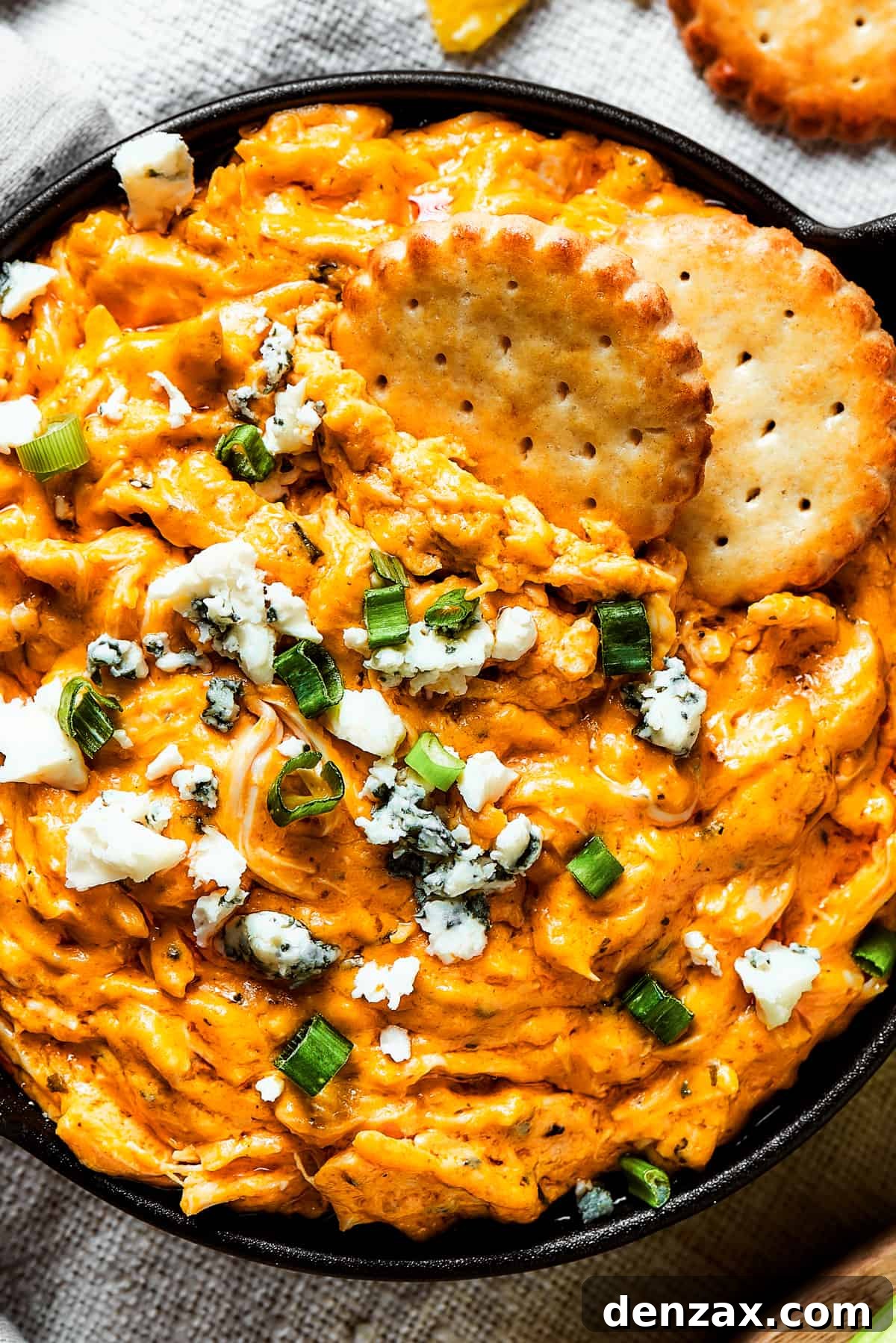 With its creamy, cheesy, spicy goodness, Crockpot Buffalo Chicken Dip is a favorite for parties, game days, movie night, and more! Two crackers dipped into a dish of buffalo dip.