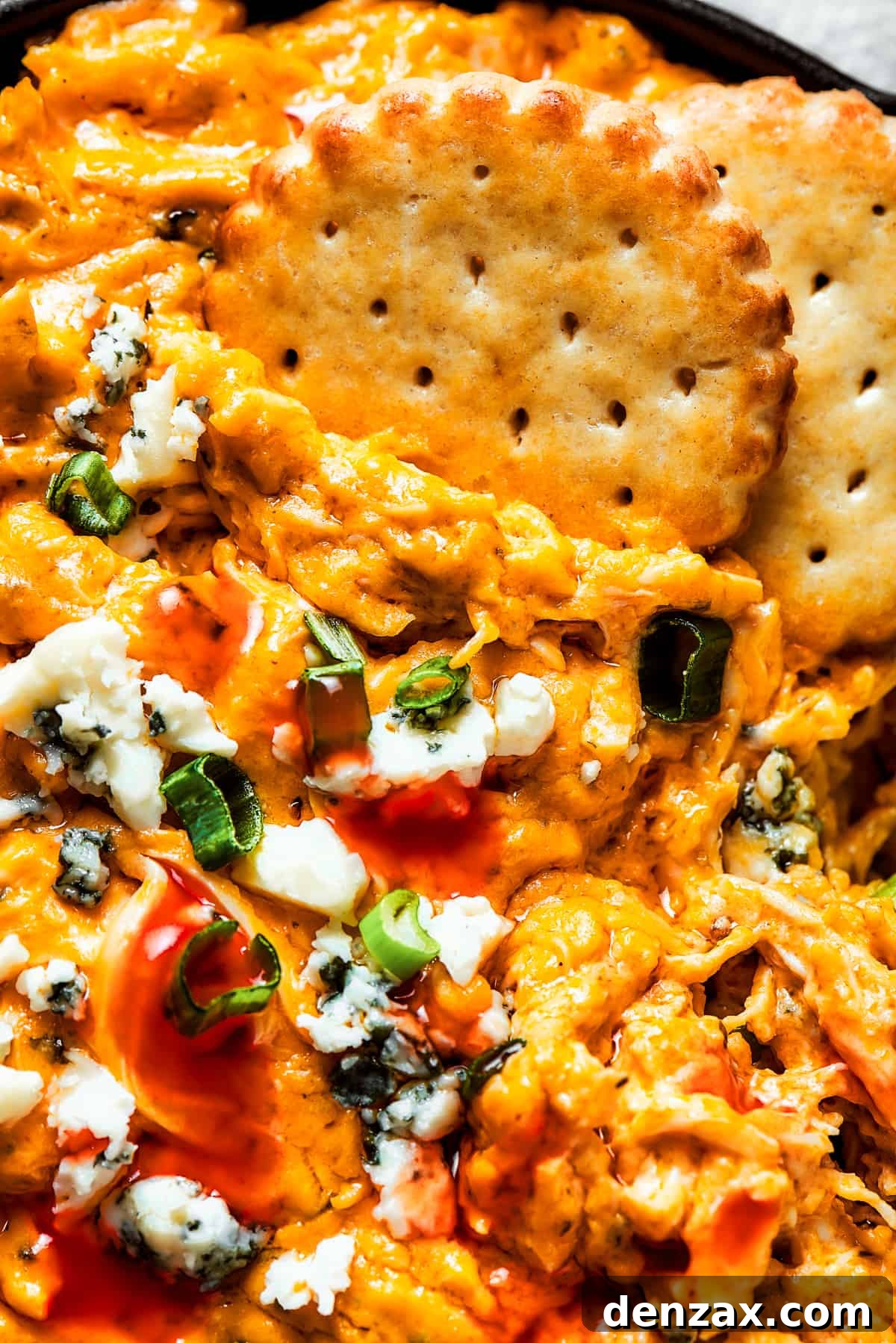 With its creamy, cheesy, spicy goodness, Crockpot Buffalo Chicken Dip is a favorite for parties, game days, movie night, and more! Close-up image of crackers dipped into a dish of buffalo dip.