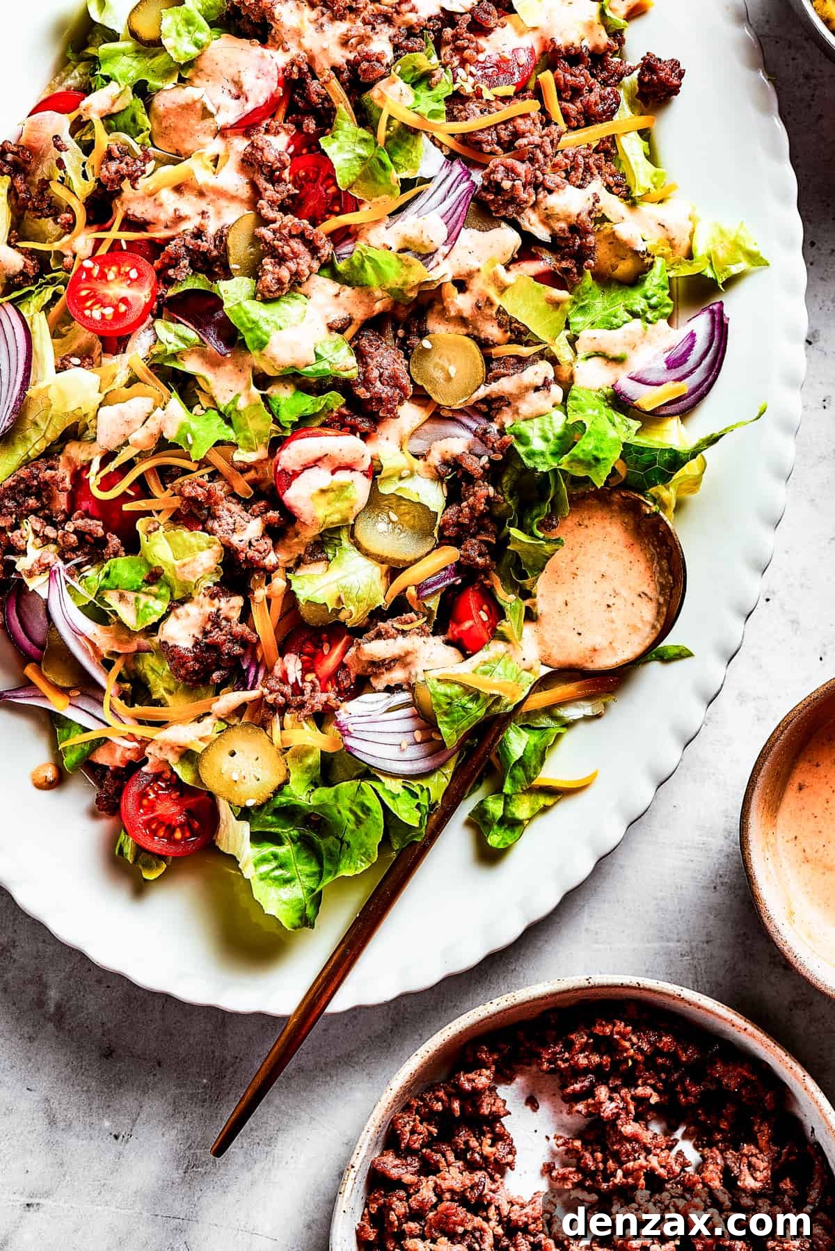 Close-up of a Big Mac Salad with red onion, ground beef, shredded cheese, and more.