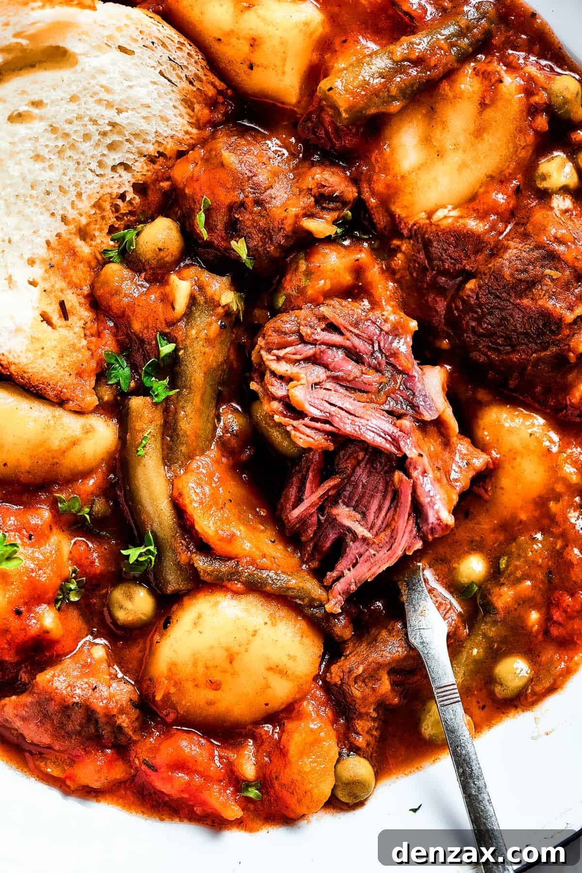 Close-up shot of a piece of white bread dipped in Mulligan stew.