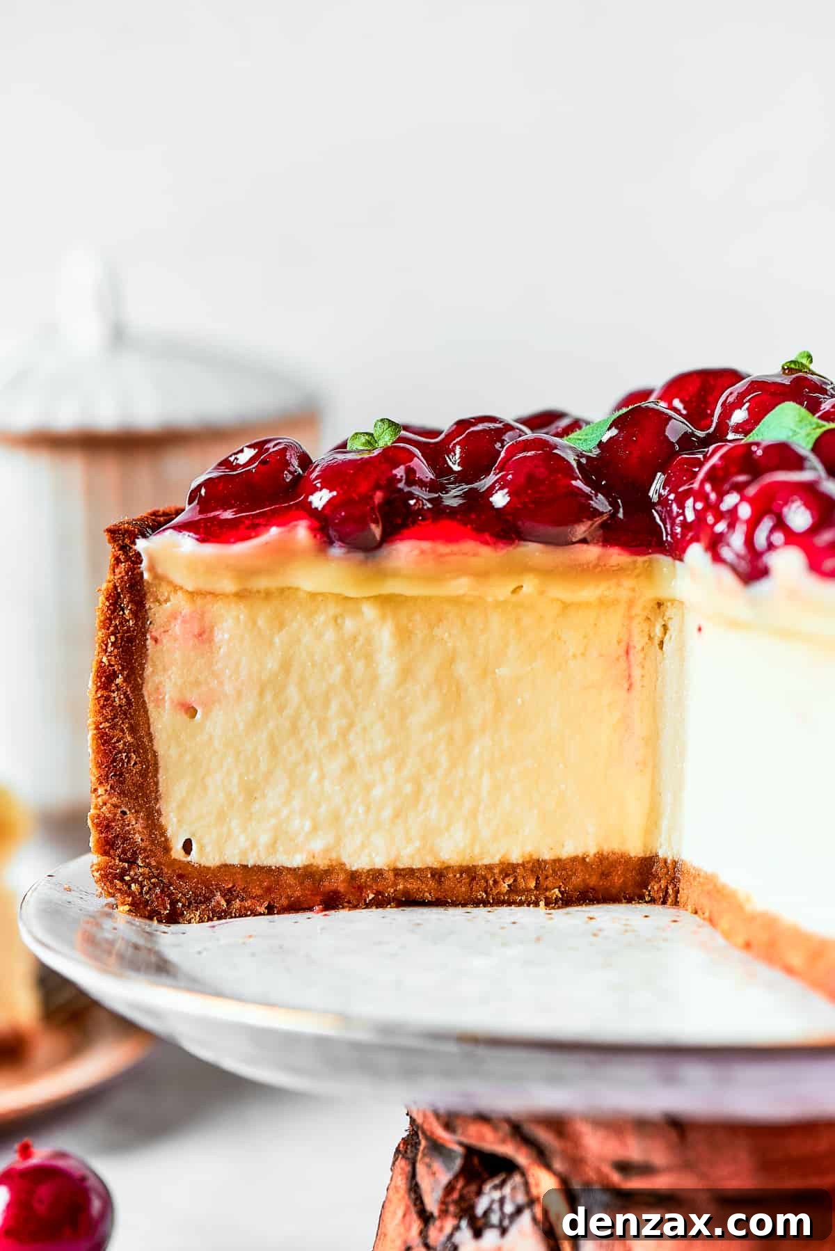 Close-up image of a cheesecake topped with cherries and placed on a cake stand.