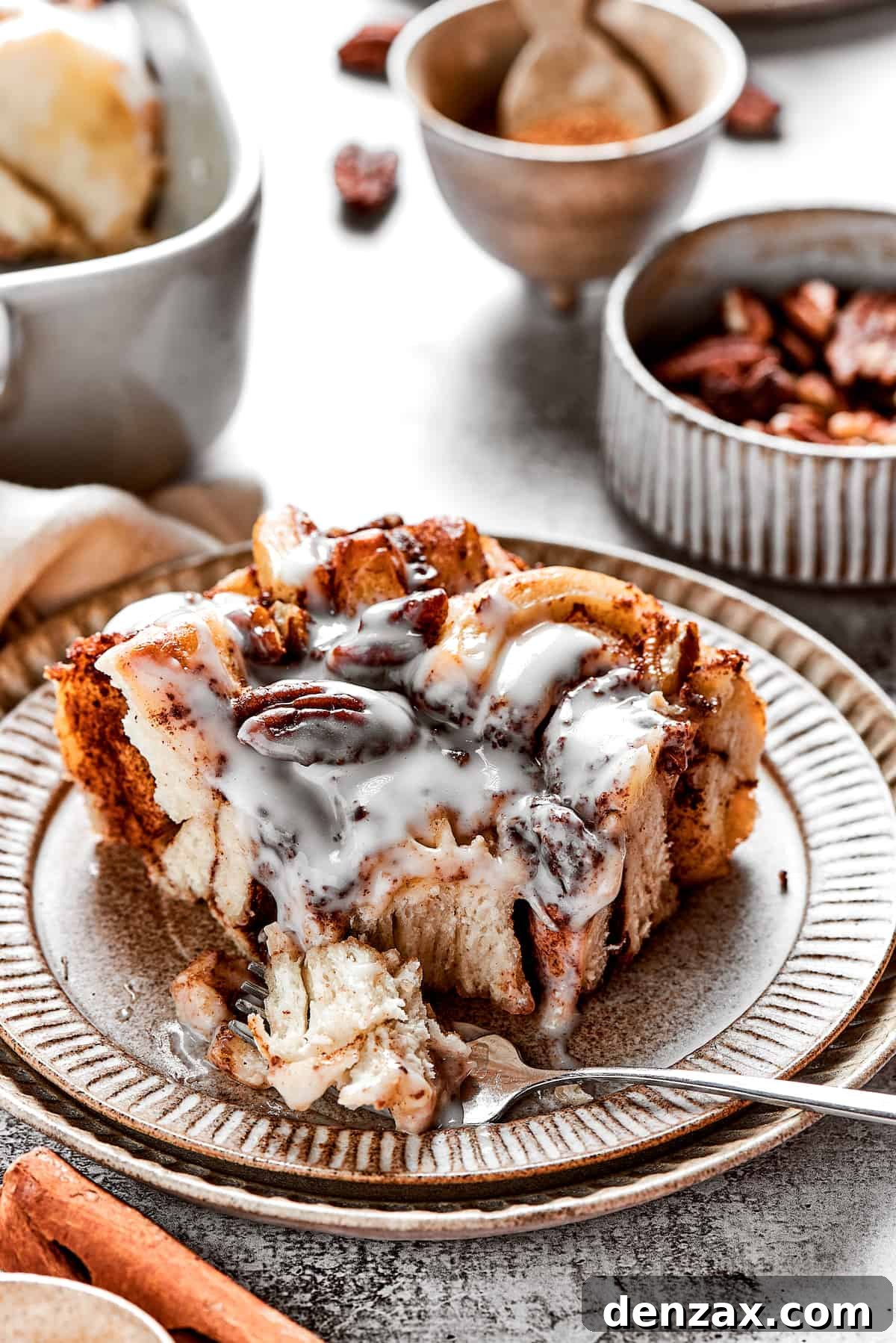 Cinnamon Roll Casserole Breakfast Bake Recipe 2 A square of cinnamon roll casserole on a plate with icing, with a fork taking a bit