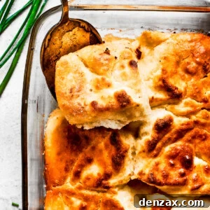 A serving spoon removing a corner piece from a pan of biscuits.
