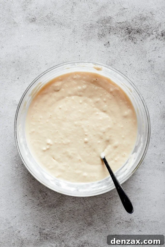 A mixing bowl with biscuit dough and a spoon