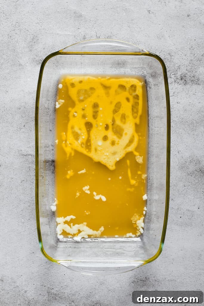 A rectangular baking dish with melted butter in it