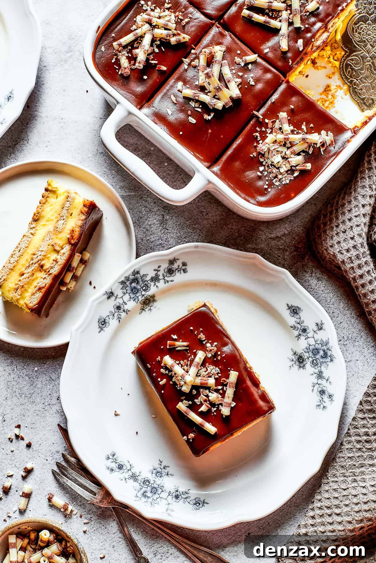 Chocolate eclair cake is loaded with creamy and smooth pudding, decadent chocolate ganache, and tender cookies, and it's so easy to make. Overhead shot of chocolate eclair cake in a baking dish with slices served on plates.