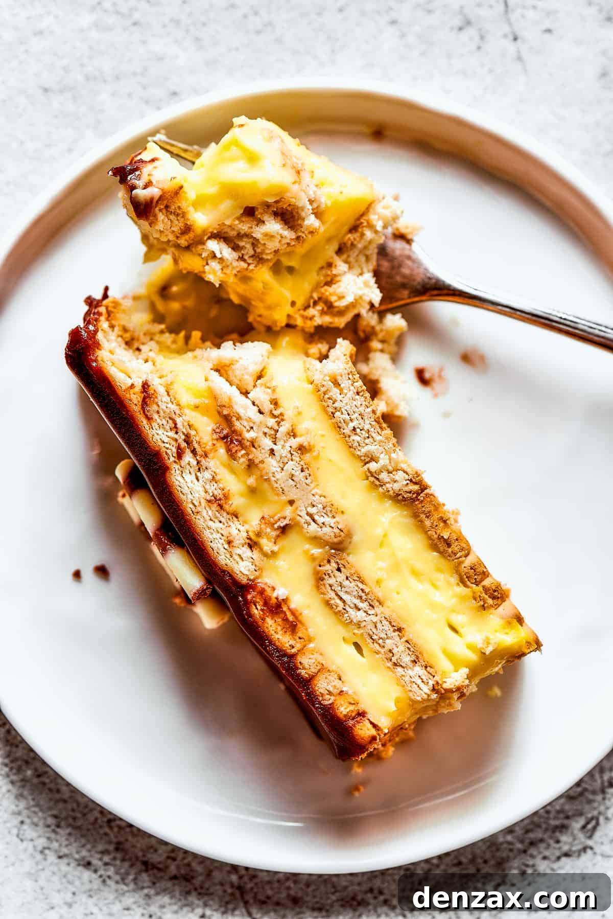 Chocolate eclair cake is loaded with creamy and smooth pudding, decadent chocolate ganache, and tender cookies, and it's so easy to make. Piece of chocolate eclair cake on a plate with a fork.