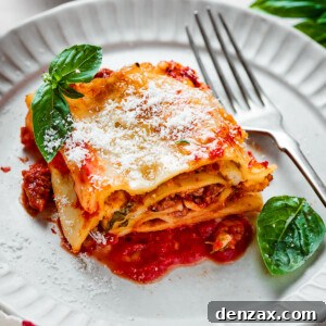 A lasagna roll on a plate with basil leaves and a fork.